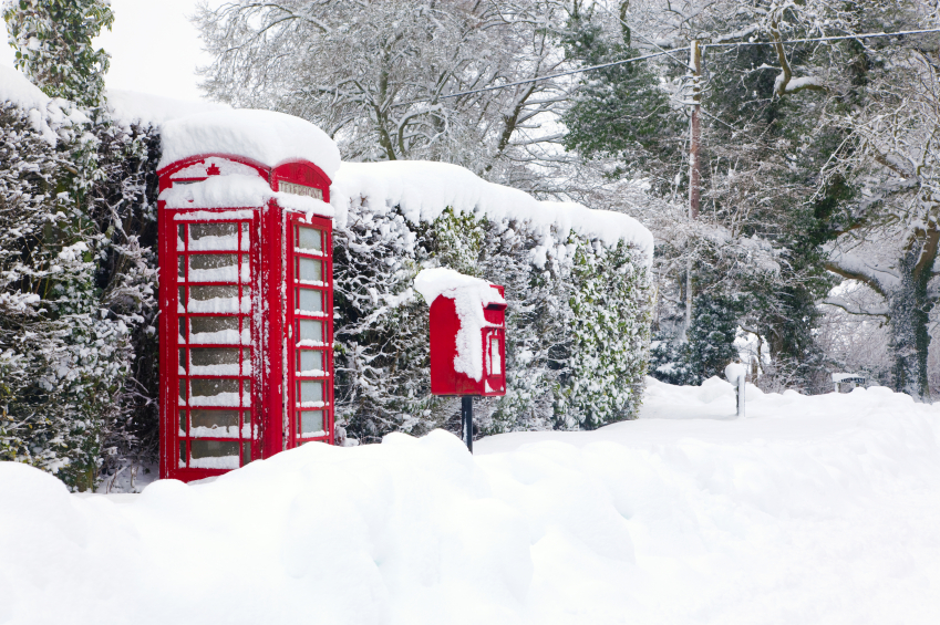 A red British telephone and post box in the snow in February.