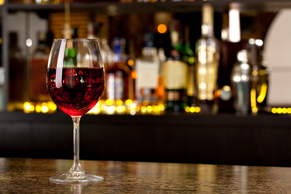Picture of a glass of wine with the bar in the background. 