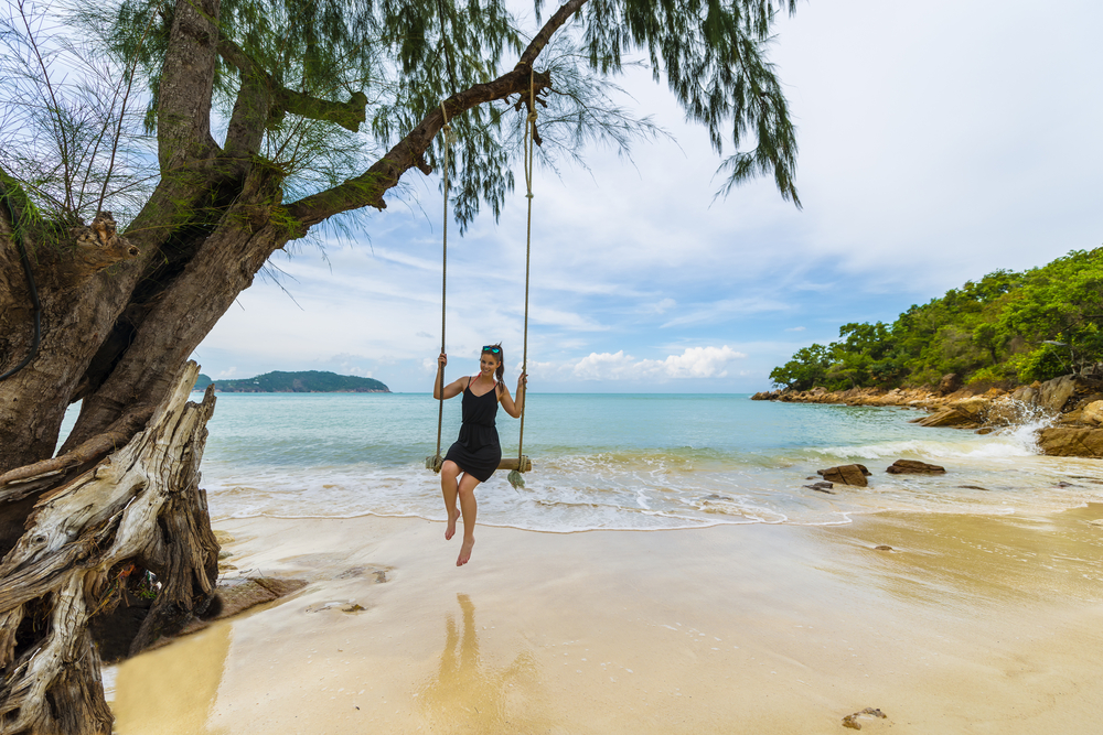 Caucasian woman on wooden swing in Koh Phangan, Thailand. 